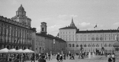 Vue monochrome de la Piazza Castello à Turin, en Italie, mettant en valeur l'architecture historique et la vie publique animée.
